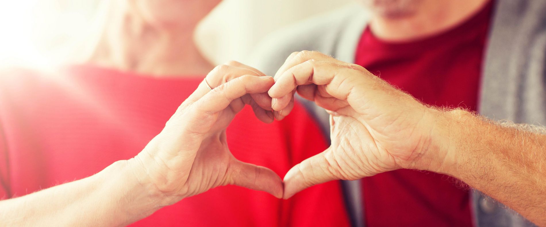 Ein Mann und eine Frau bilden ein Herz mit ihren Händen als Symbol für einen Herzinfarkt